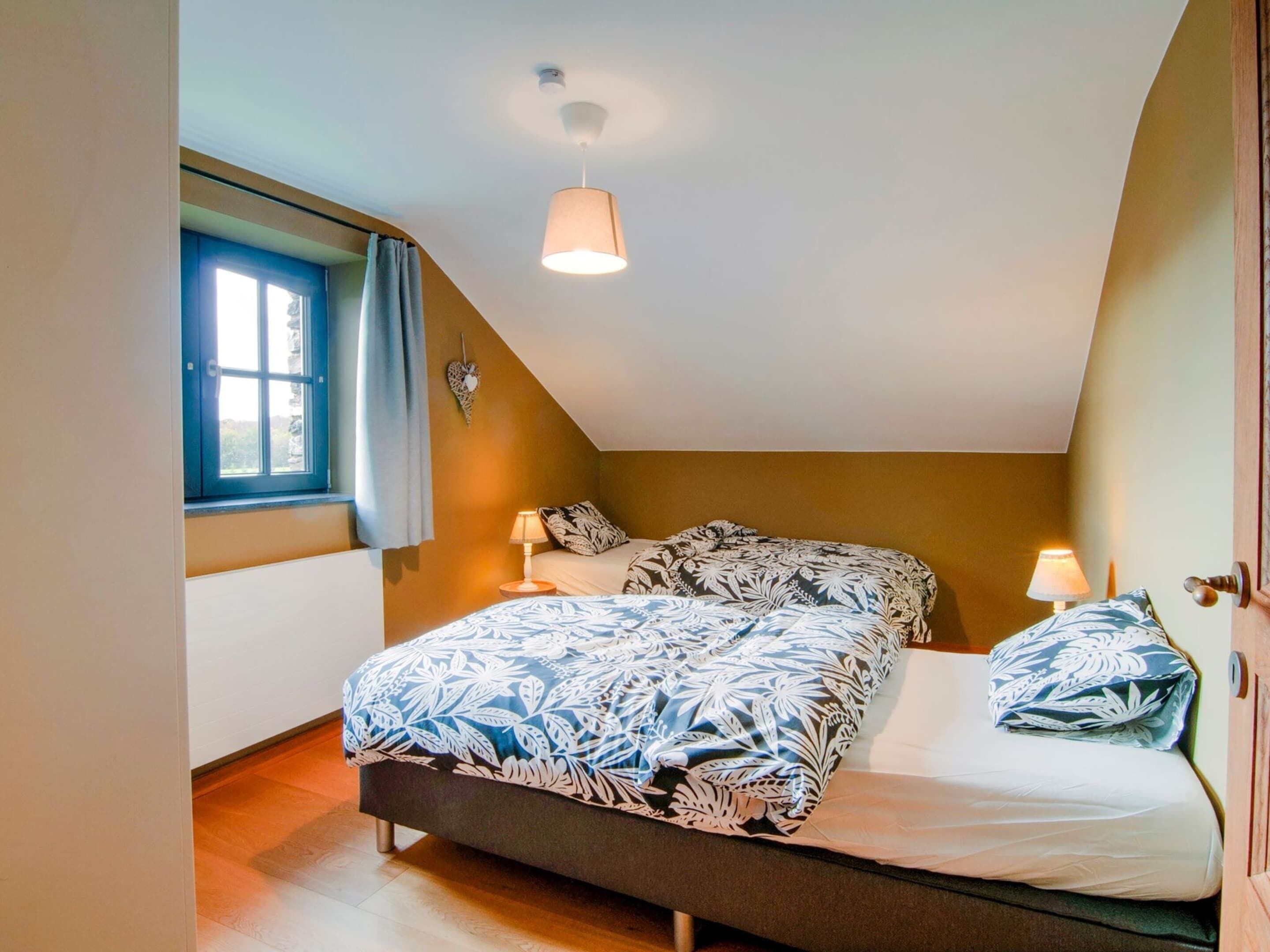 A bedroom with a bed, two bedside lamps, a window with curtains, and a ceiling light.