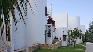 A courtyard with white buildings, stone walls, and green grass. - Splendid Holiday Home With Swimming Pool (Rethymno)