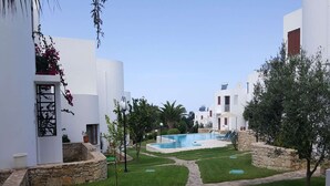 A pool area with a stone pathway, surrounded by white buildings with balconies and potted plants. - Splendid Holiday Home With Swimming Pool (Rethymno)