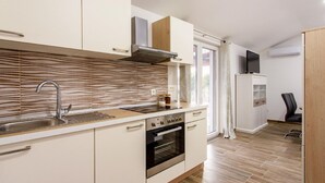 Una cocina moderna con armarios blancos, un lavamanos de acero inoxidable, horno empotrado y campana extractora.