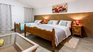 Un dormitorio con cama de madera, dos mesitas de noche con lámparas, un cuadro en la pared y una mesita de cristal con una vela.