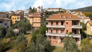 A residential area with multi-story buildings, some with balconies, surrounded by greenery and trees. - Serene Lakeview Apartment (Tuoro sul Trasimeno)