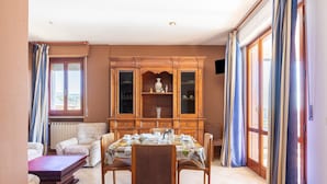 A dining room with a wooden cabinet, a dining table set with plates and cups, and a sofa. - Serene Lakeview Apartment (Tuoro sul Trasimeno)