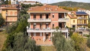 A multi-story residential building with a tiled roof, balconies, and a garden area. - Spacious Lakefront Apartment (Tuoro sul Trasimeno)