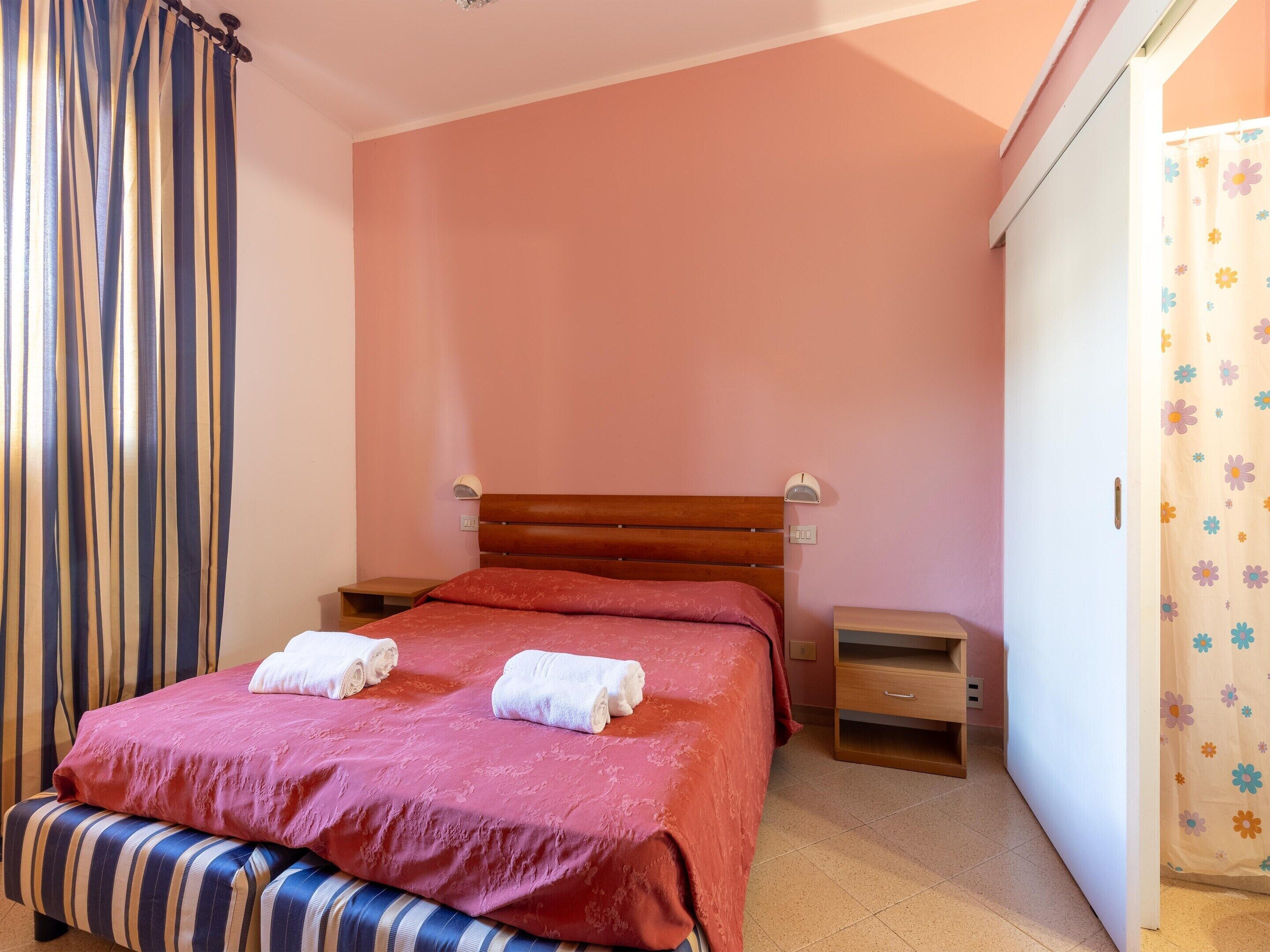 A bedroom with a single bed, a bedside table, a nightstand, and a wardrobe.