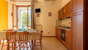 A dining area with a table set for four, wooden chairs, and a view through an open door to a balcony. - Spacious Lakefront Apartment (Tuoro sul Trasimeno)