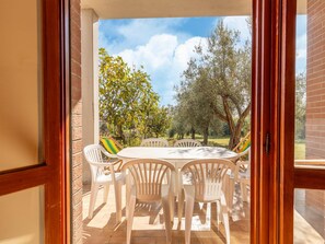 Un patio con una mesa y sillas, un muro de ladrillo y vistas a árboles y cielo.