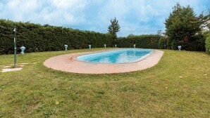 A swimming pool with a paved deck, surrounded by a well-maintained lawn and hedges. - Spacious Lakefront Apartment (Tuoro sul Trasimeno)