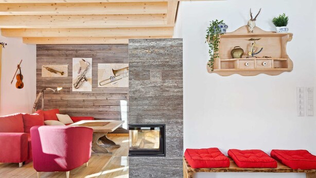 A cozy living room with a fireplace, red furniture, and a wooden ceiling.