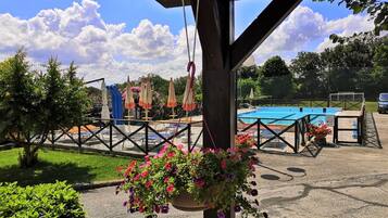 Relax by the pool surrounded by lush greenery and a wooden pergola, offering shade and a serene atmosphere.