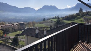 A view from a balcony overlooking a valley with mountains in the distance, houses, and a clear sky. - Castle in Clouds; A Holiday Home (Stenico)