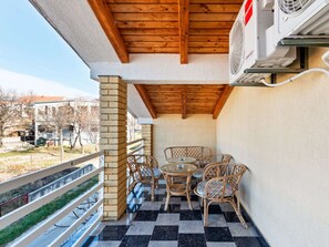 Un balcon doté d’un sol à carreaux, de chaises en osier et d’une table.