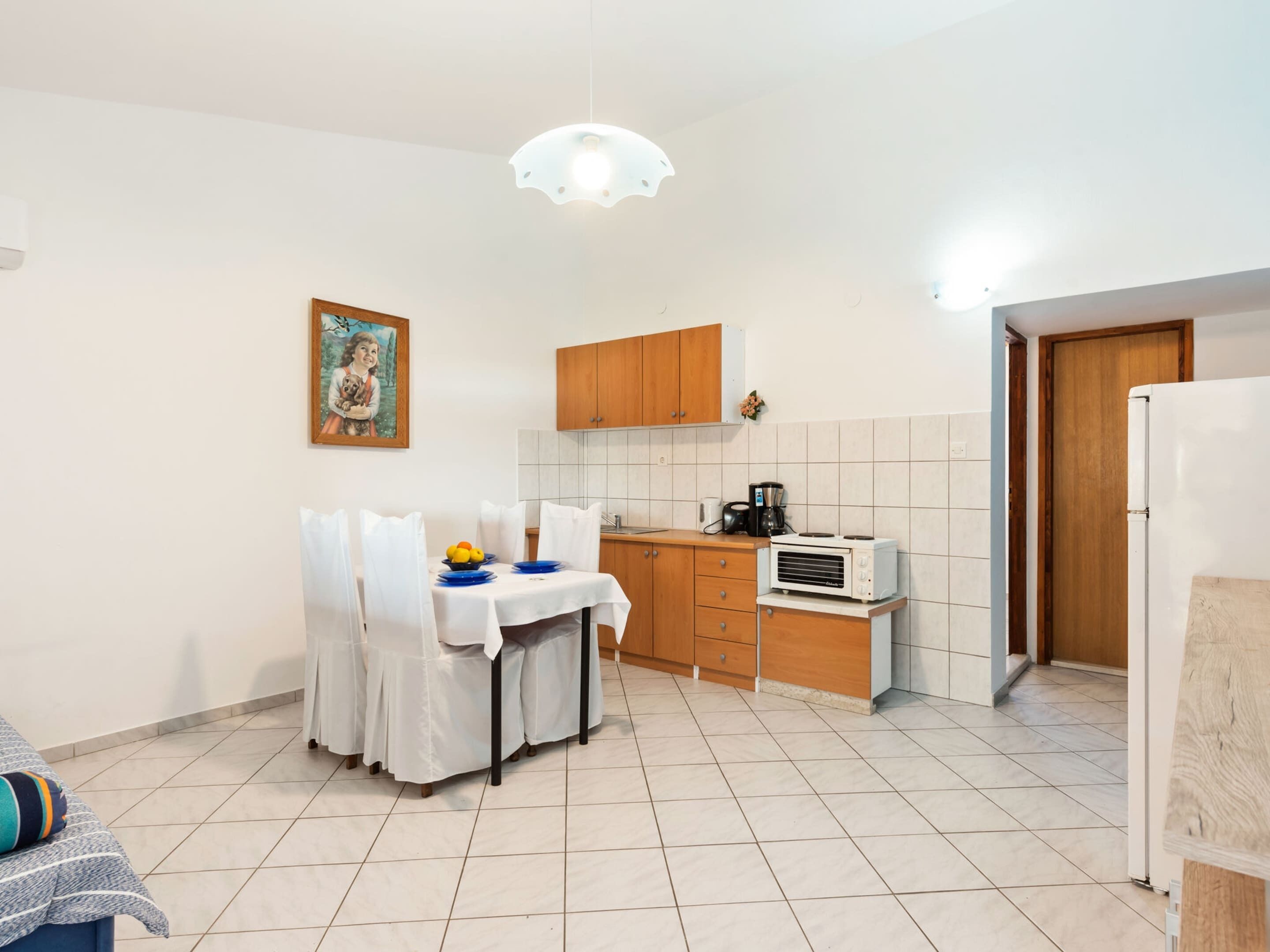 A compact kitchen with a dining table, a coffee maker, and a refrigerator.