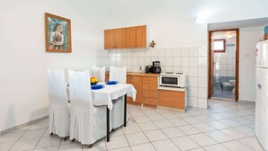 Cozinha compacta com mesa de jantar, armários de madeira e painel de azulejos brancos.