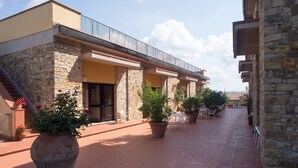 A stone building with a covered patio, outdoor seating, and potted plants.