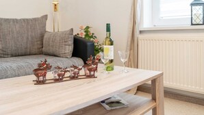 Olohuone, jossa on sohva, puinen pöytä, pullollinen viiniä ja lasit sekä koristeellinen poronhahmo.