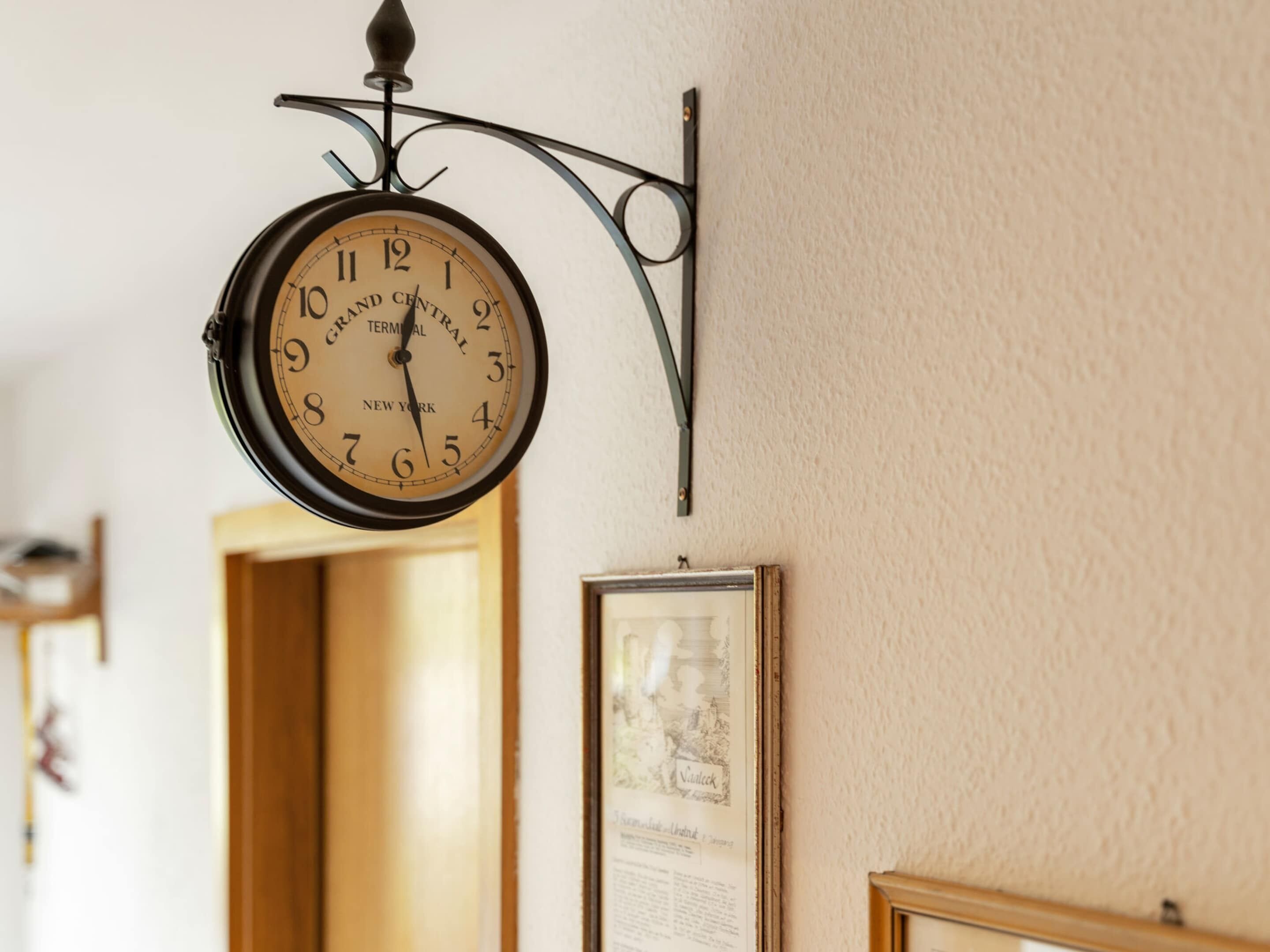 A wall-mounted clock with a classic design, featuring the brand name and location.