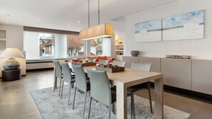 Uma área de jantar moderna com mesa de madeira, cadeiras cinzas e tapete cinza.