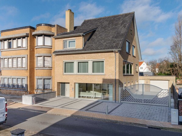 Un bâtiment moderne doté d’un toit en pente, de grandes fenêtres et d’une entrée en verre.