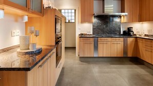 Uma cozinha moderna com armários de madeira, bancadas de granito e eletrodomésticos de aço inoxidável.