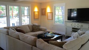 A living room with a sofa, coffee table, TV, and wall-mounted lights. - Downtown Location, Uptown Elegance! Re-Modeled “Murphys Original School House" (Murphys)