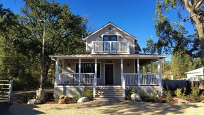 A two-story house with a front porch, a balcony on the upper floor, and a gravel driveway. - Downtown Location, Uptown Elegance! Re-Modeled “Murphys Original School House" (Murphys)