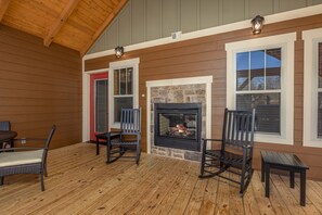 A covered porch with wooden flooring, a stone fireplace, and two rocking chairs. - Wet and Wild (Gatlinburg)