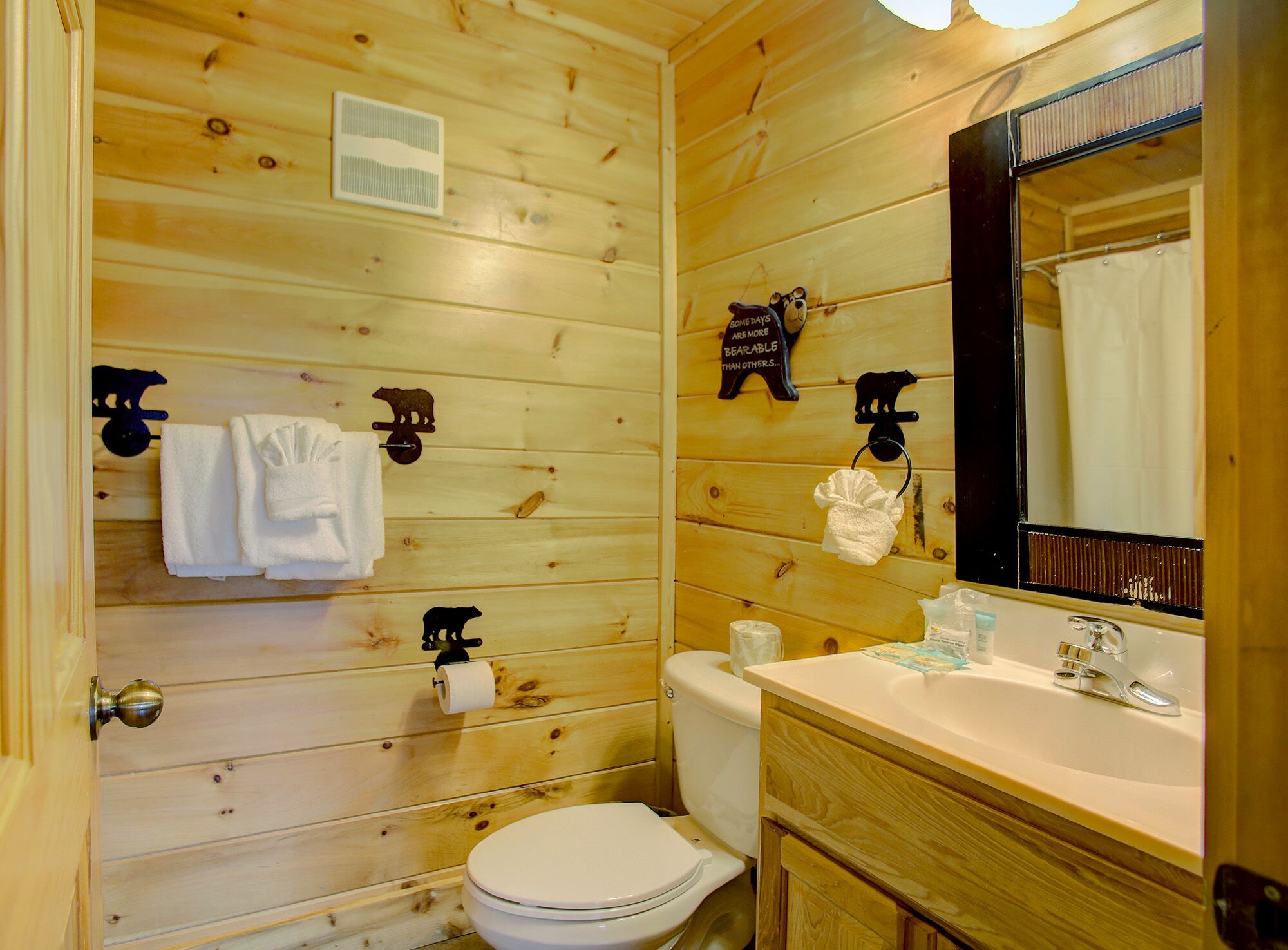 Une salle de bain aux murs lambrissés, équipée de toilettes, d’un lavabo et d’un porte-serviettes.