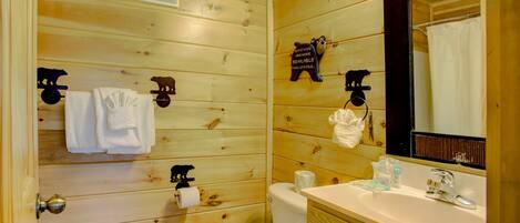 Une salle de bain aux murs lambrissés, équipée de toilettes, d’un lavabo et d’un porte-serviettes.