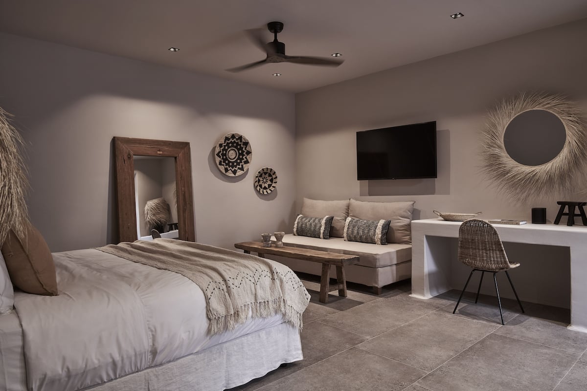 A bedroom with a bed, bedside table, chair, desk, and TV.