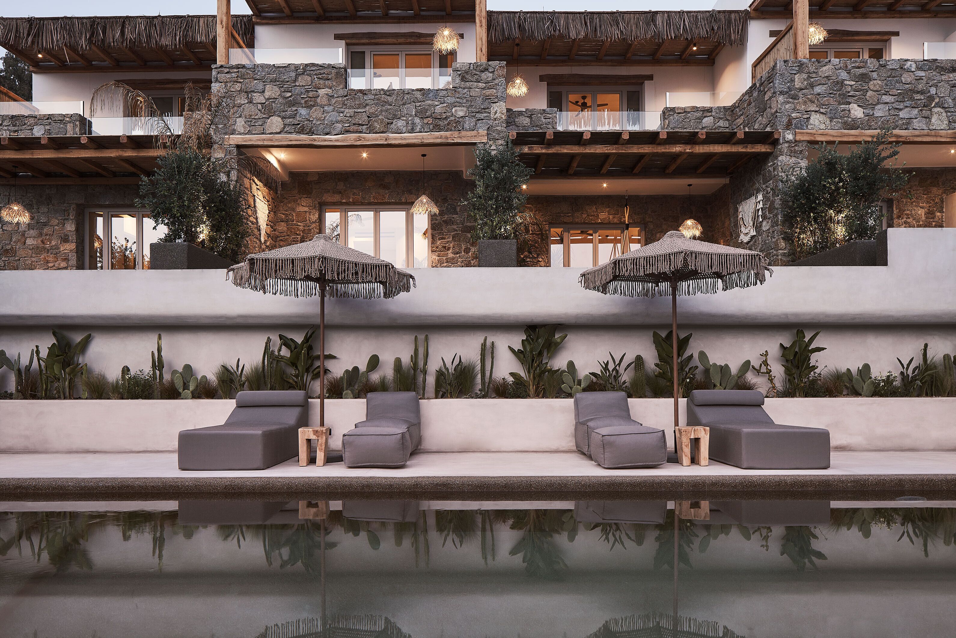 Ein modernes Resort mit Pool, Außenbereich zum Sitzen und einer Steinfassade.