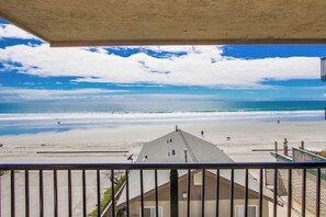 A beach view from a balcony with a clear sky and ocean.