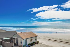 A beachfront property with a small house, a visible garage, and a clear view of the ocean.