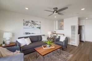 A modern living room with a grey sofa, a wooden coffee table, and a ceiling fan.