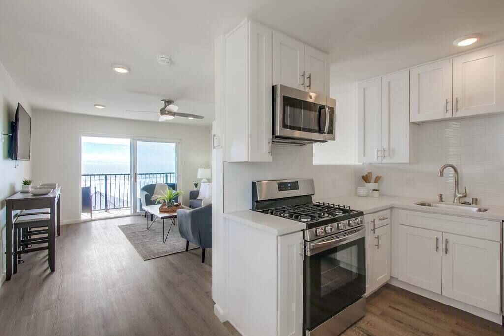 A modern kitchen with white cabinets, a stainless steel stove, and a microwave.