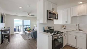 A modern kitchen with white cabinets, a stainless steel stove, and a microwave.