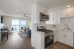 Une cuisine moderne avec des meubles blancs, une cuisinière en acier inoxydable et un four à micro-ondes.