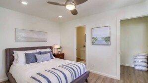A bedroom with a bed, a ceiling fan, and a nightstand. - The Buccaneer House - Oceanfront (Oceanside)