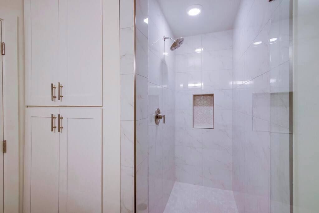 A bathroom with a shower, a toilet, and a cabinet.