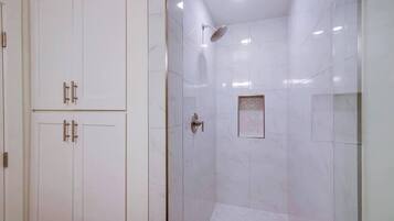 A bathroom with a shower, a toilet, and a cabinet.