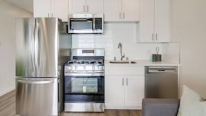 A compact kitchen with a refrigerator, microwave, stove, oven, sink, and dishwasher.