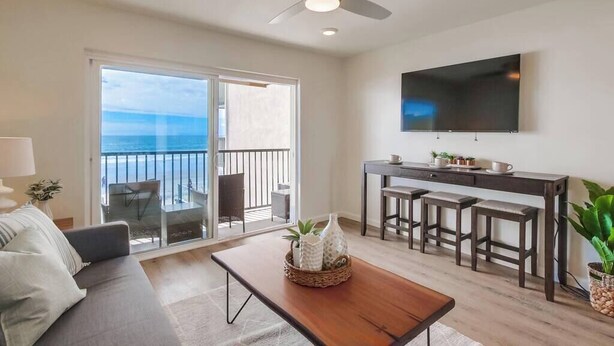 A living room with a sofa, a coffee table, and a TV mounted on the wall.
