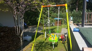 A playground with a swing set, a slide, and a small green and yellow play structure. - '4er Müggelwaldzimmer' quiet + cozy apartment in Köpenick m. Garden area (Bezirk Treptow-Köpenick)