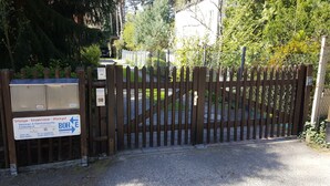 A gated entrance with a sign indicating services like "Umzüge - Einzimmermöbel - Stückgut" and contact information for "Auto-Tel." - '4er Müggelwaldzimmer' quiet + cozy apartment in Köpenick m. Garden area (Bezirk Treptow-Köpenick)