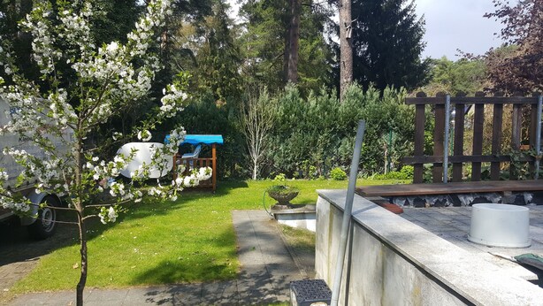 A garden with a white car, a blue tarp-covered structure, and a wooden fence. - '4er Müggelwaldzimmer' quiet + cozy apartment in Köpenick m. Garden area (Bezirk Treptow-Köpenick)