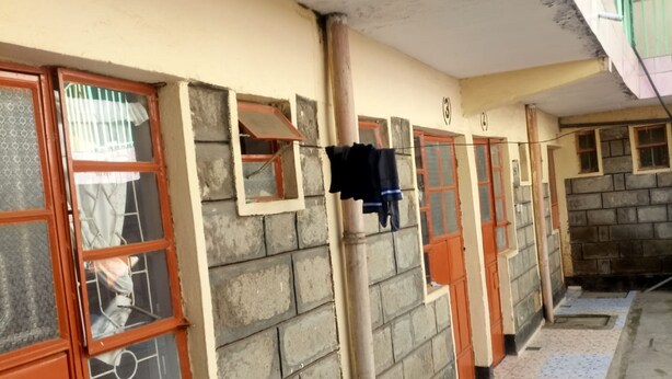 Um corredor com piso de azulejos, parede de tijolos e portas com painéis de vidro.