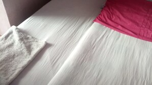 Uma cama com roupa de cama branca e um cobertor rosa.