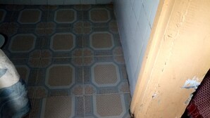 A small, tiled bathroom with a patterned floor and a visible water leak on the wall. - Eldama Lodge (Gilgil)