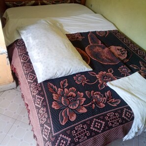 A bed with a patterned bedspread, a white pillow, and a white towel. - Eldama Lodge (Gilgil)