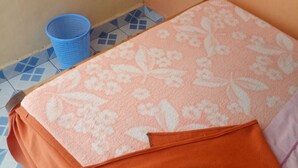 A bed with a floral-patterned blanket and a brown pillow. - Eldama Lodge (Gilgil)